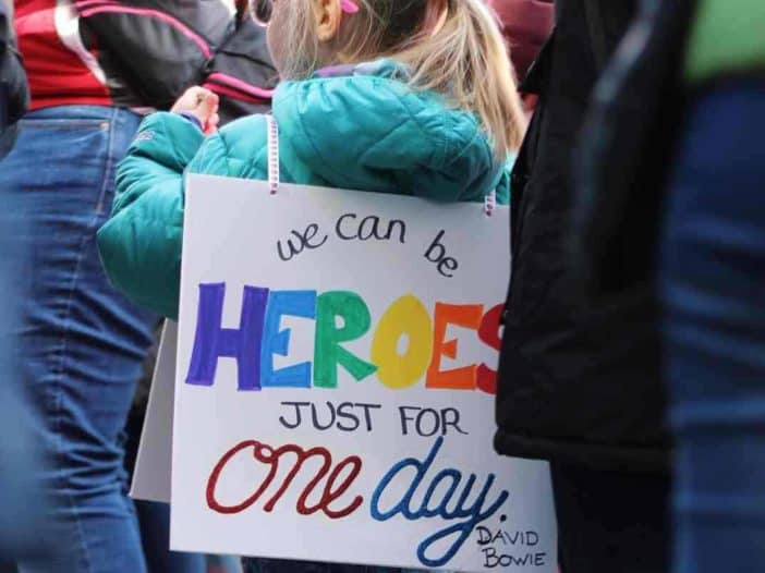 Kind trägt Schild auf dem rücken auf dem steht we can be heroes just for one da
